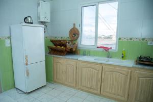 a kitchen with a white refrigerator and a window at Dar Beya ( APP S+2 ) in Tozeur