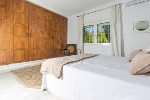 - une chambre avec un lit blanc et des placards en bois dans l'établissement LXR Benalmadena 4 Hab. Paradise Villa, à Benalmádena