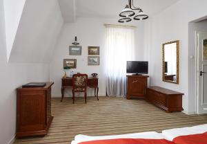 a bedroom with a bed and a table and a television at Pałac Myślęcinek in Bydgoszcz