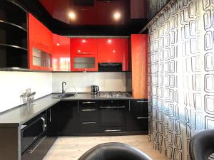 a kitchen with red cabinets and black counters at Вокзал ТД Пирамида 2-х комнатная квартира in Petropavlovsk