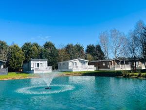 una fuente en medio de un estanque con casas en Sutton Lodge with Hot Tub, en York