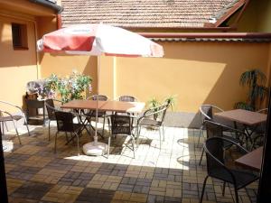 eine Terrasse mit Tischen, Stühlen und einem Sonnenschirm in der Unterkunft Penzion Romance in Břeclav