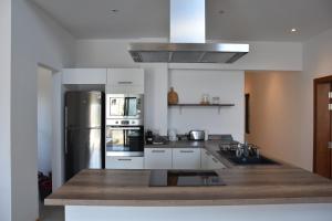 a kitchen with white cabinets and a stainless steel refrigerator at Cap Sud Apartment in Tamarin