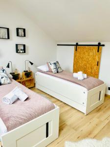 2 camas num quarto com pisos em madeira e paredes brancas em Szczyrkowskie SKI & FUN 16 - z widokiem na góry em Szczyrk