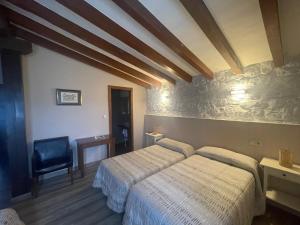 a bedroom with two beds and a chair at Posada La Solana in Santillana del Mar