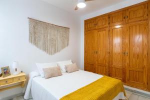 セビリアにあるApartamento con garaje, centro de Sevillaの白いベッドと木製キャビネット付きのベッドルーム1室
