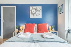 a blue bedroom with a large bed with red pillows at Cambridge Home Suite 4 in Cambridge