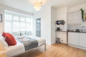een witte slaapkamer met een bed en een keuken bij Stylish Studio 4 with Kitchenette by CB Stays no minimum stays in Cambridge