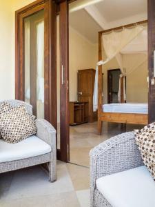 a room with two chairs and a bed with a mirror at Villa 7, Secret Garden, Kerandangan, near Senggigi in Mataram