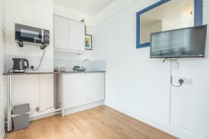 een keuken met witte kasten en een tv aan de muur bij Stylish Studio 4 with Kitchenette by CB Stays no minimum stays in Cambridge
