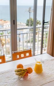 een kom sinaasappels en een glas sinaasappelsap op een tafel met een raam bij Ático de Lujo con vistas al mar, primera línea Playa del Postiguet in Alicante