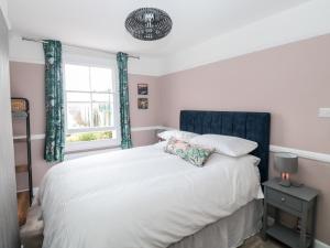 a bedroom with a bed with a blue headboard and a window at Rose Cottage in Teignmouth