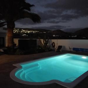 una piscina por la noche con una palmera en Vivienda Vacacional Casa del Erizo - Ecofinca, en Nazaret