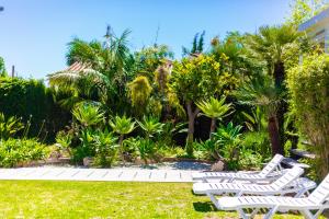 2 chaises blanches dans un jardin planté de palmiers dans l'établissement LXR Benalmadena 4 Hab. Paradise Villa, à Benalmádena