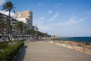 eine Promenade entlang eines Strandes mit Gebäuden und dem Meer in der Unterkunft Homely Apartments Las Salinas in Torrevieja