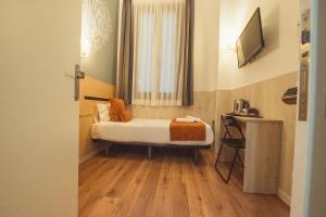 Una pequeña habitación con una cama y una ventana. en Hostal Live Natura Barcelona, en Barcelona