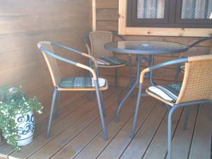 3 sillas y una mesa en un porche en Rybacka chata, en Rusinowo