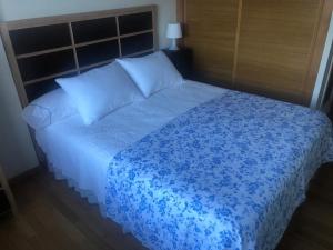 een slaapkamer met een bed met blauwe lakens en kussens bij Fantástico apartamento con garaje en Valdoviño. in Valdoviño