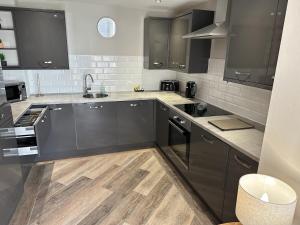 a kitchen with black cabinets and wooden floors at Beach Pad - ground floor - pet friendly in Cleveleys