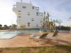 un edificio blanco con 2 sillas y una piscina en Appealing holiday home in Roldan with garden, en Roldán