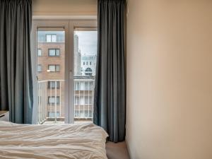 ein Schlafzimmer mit einem Bett und einem großen Fenster in der Unterkunft Attractive apartment in Koksijde with balcony in Koksijde