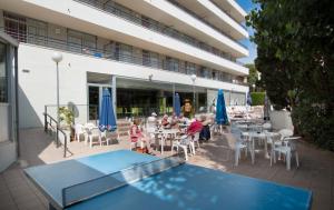 un grupo de niños sentados en una mesa junto a una piscina en Medplaya Aparthotel Esmeraldas, en Tossa de Mar