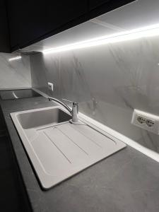 a white sink in a kitchen with a light at Alma Rose Apartment in Korçë
