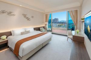 ein Schlafzimmer mit einem großen Bett und einem großen Fenster in der Unterkunft Hong Kong Gold Coast Hotel in Hongkong