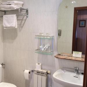 ein Badezimmer mit einem Waschbecken, einem WC und einem Spiegel in der Unterkunft Hostería los Sauces in Maoño