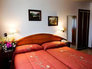 - une chambre avec un grand lit rouge et deux photos sur le mur dans l'établissement Hostería los Sauces, à Maoño