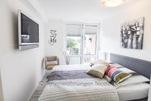 een witte slaapkamer met een bed en een televisie bij Deichresidenz Stein in Stein