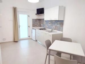 uma cozinha com armários brancos e uma mesa e cadeiras em Casa Vacanze Onda Azzurra (Deluxe) em Peschici