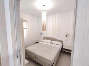 een witte slaapkamer met een bed en een kroonluchter bij Casa Vacanze Onda Azzurra (Deluxe) in Peschici