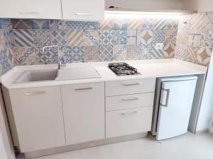Casa Vacanze Onda Azzurra (Deluxe) في بيسكيتشي: مطبخ أبيض مع حوض وموقد