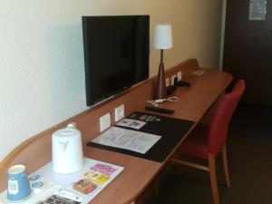 a desk in a hotel room with a television on it at Kyriad Montargis Amilly in Amilly