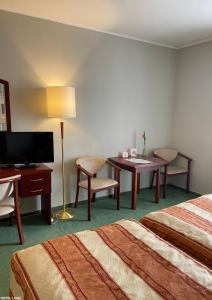 a hotel room with two beds and a desk and a table at Hotel Lival in Gdańsk