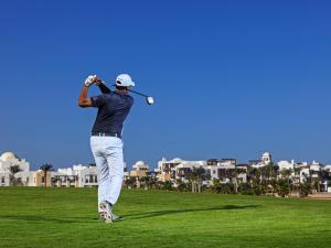 Ancient Sands Golf Resort and Residences في الغردقة: رجل يلعب الغولف على ملعب للجولف