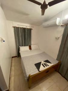 Cama pequeña en habitación pequeña con ventilador en The Sea Shelter Home Stay, en Mahabalipuram