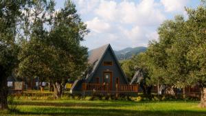 a large blue house with a porch and trees at Verde Blu Bungalow in Edremit