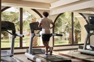 Ein Mann auf einem Laufband in einem Fitnessstudio mit Blick aus dem Fenster. in der Unterkunft Fanar Hotel & Residences in Salalah