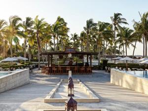 a resort with a bar and a pool and palm trees at Fanar Hotel & Residences in Salalah