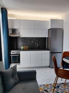 Apartment Augustini في كريس: مطبخ مع دواليب بيضاء وثلاجة