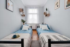 two beds in a room with white walls at Wielopole Homes by LoftAffair in Kraków