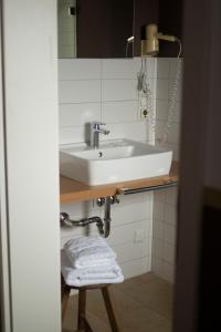 a bathroom with a white sink and a stool at Kastanienhof Pfettrach in Altdorf