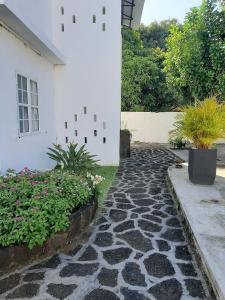 einen Steinweg neben einem weißen Gebäude mit Pflanzen in der Unterkunft Le Beau Manguier Residence in Pereybere