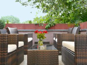 eine Terrasse mit Korbstühlen und einem Tisch mit einer Blumenvase in der Unterkunft Hotel Bonverde (Wannsee-Hof) in Berlin