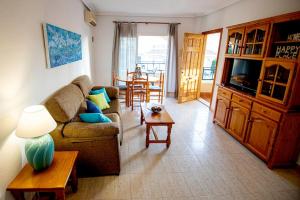 uma sala de estar com um sofá e uma mesa em Disfruta de la playa y piscina, acogedora casa em Santa Pola