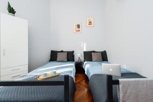 two beds in a room with a laptop on it at Wielopole Homes by LoftAffair in Kraków