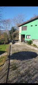 a green building with a bench in front of it at La casina de castiello in Arriondas