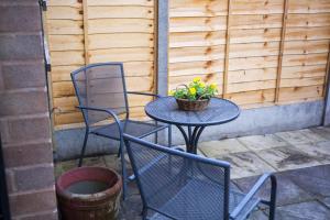 two chairs and a table with a plant on a patio at The Great William St. Cottage in Stratford-upon-Avon